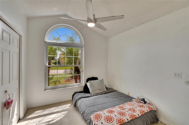 carpeted bedroom with lofted ceiling, ceiling fan, and a textured ceiling