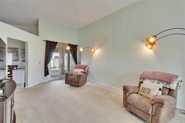 sitting room with carpet floors, high vaulted ceiling, and baseboards