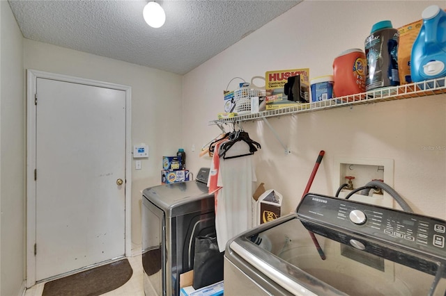 washroom featuring laundry area, a textured ceiling, and washing machine and clothes dryer