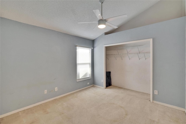 unfurnished bedroom with carpet, lofted ceiling, a closet, ceiling fan, and a textured ceiling