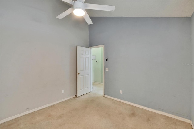 spare room with vaulted ceiling, baseboards, a ceiling fan, and light colored carpet