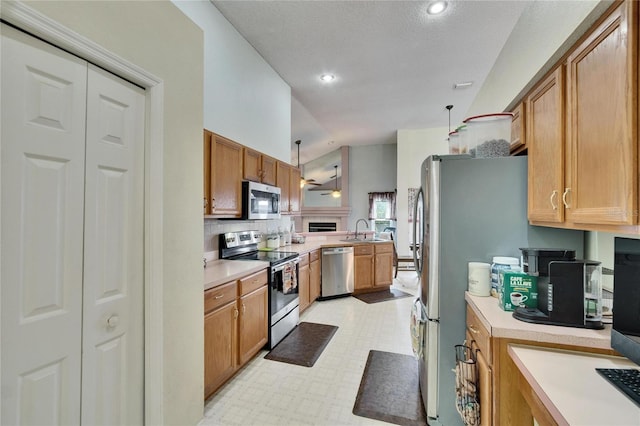 kitchen with light floors, stainless steel appliances, light countertops, a sink, and a peninsula