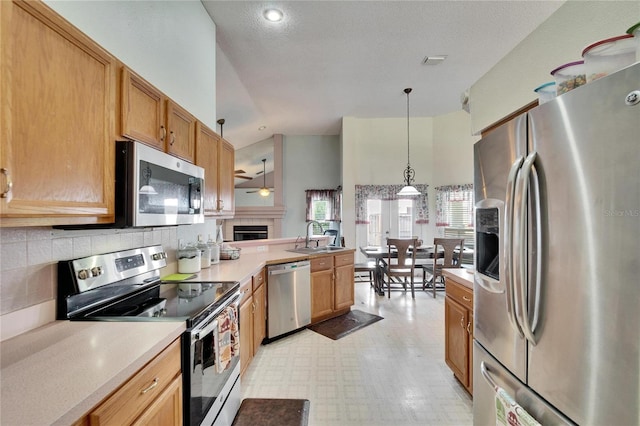 kitchen featuring a peninsula, a sink, light countertops, appliances with stainless steel finishes, and light floors