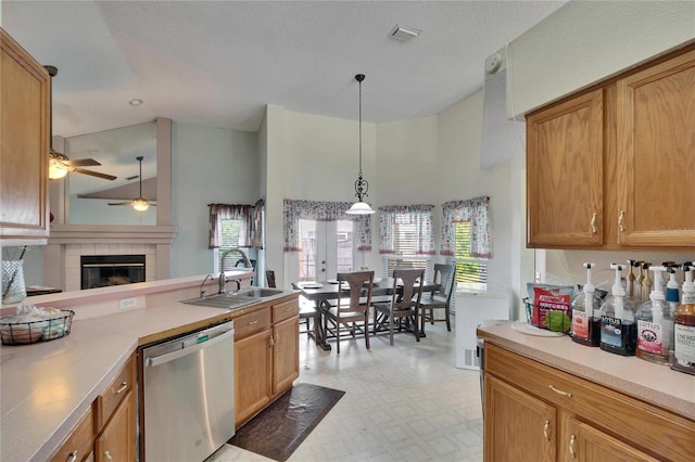 kitchen with light floors, visible vents, a tiled fireplace, stainless steel dishwasher, and a sink