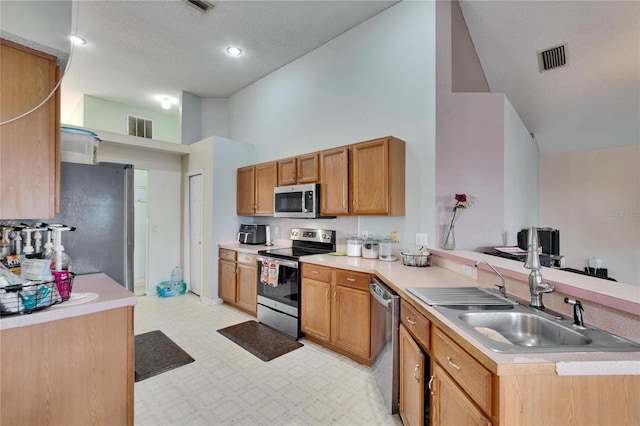 kitchen featuring light floors, appliances with stainless steel finishes, a peninsula, and visible vents