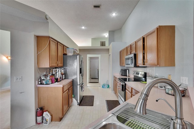 kitchen with a sink, stainless steel appliances, light floors, and light countertops