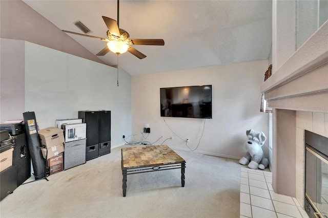 tiled living room featuring carpet floors, a fireplace, lofted ceiling, visible vents, and ceiling fan