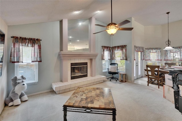 carpeted living area with high vaulted ceiling, a wealth of natural light, a fireplace, and baseboards