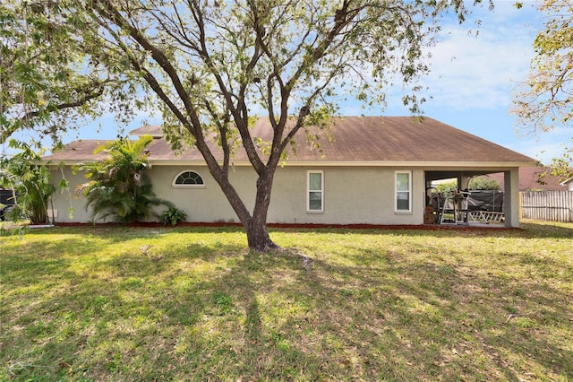 back of property featuring a lawn, fence, and stucco siding