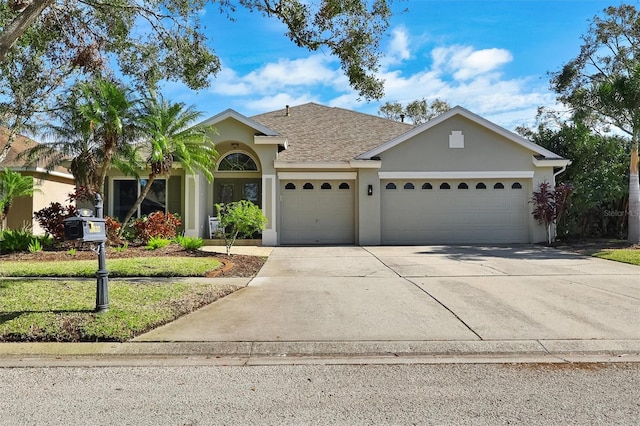 single story home with a shingled roof, concrete driveway, a garage, and stucco siding