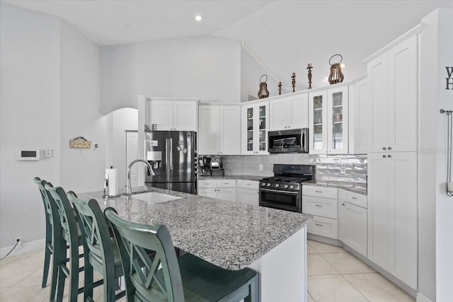 kitchen featuring a sink, white cabinetry, appliances with stainless steel finishes, light tile patterned flooring, and decorative backsplash