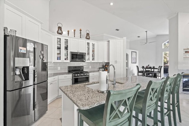 kitchen featuring tasteful backsplash, light tile patterned floors, appliances with stainless steel finishes, and white cabinetry