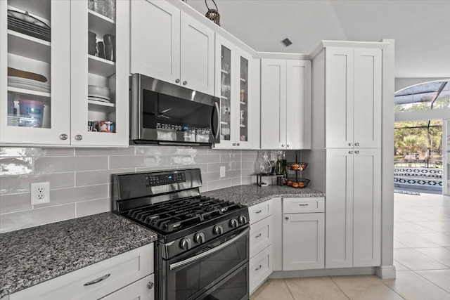 kitchen featuring decorative backsplash, dark stone countertops, white cabinets, and appliances with stainless steel finishes