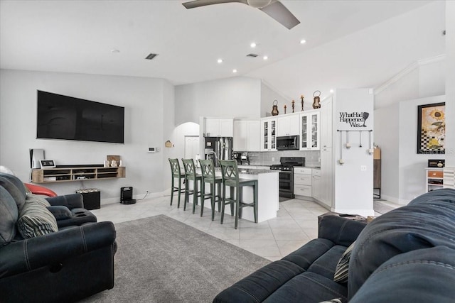 living room with arched walkways, light tile patterned floors, baseboards, and ceiling fan