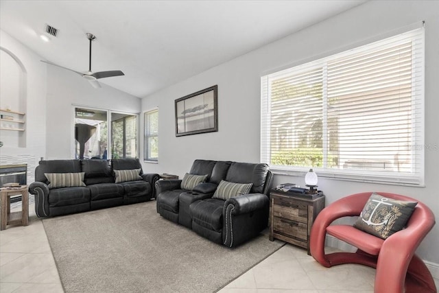 living area with light tile patterned floors, visible vents, a ceiling fan, and vaulted ceiling