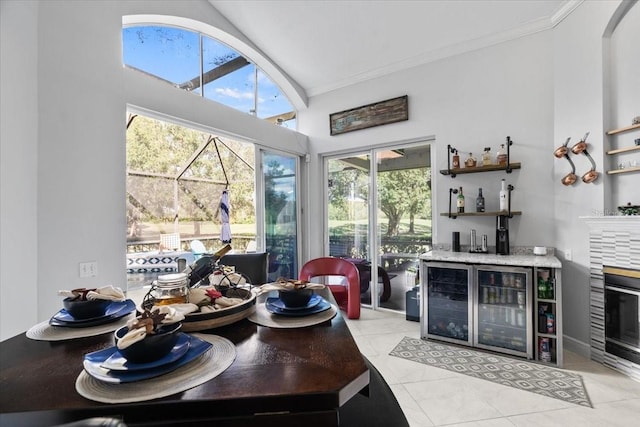 dining room with ornamental molding, wine cooler, arched walkways, light tile patterned flooring, and bar area