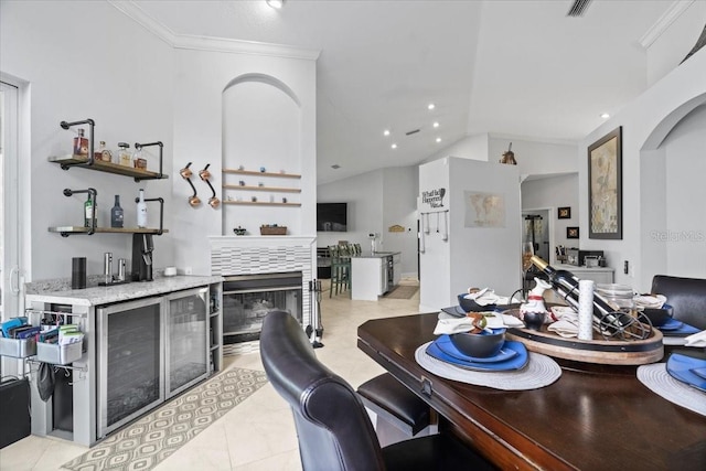 dining room with lofted ceiling, ornamental molding, light tile patterned floors, recessed lighting, and wet bar