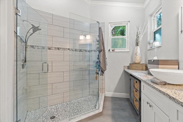 bathroom with a shower stall, tile patterned flooring, crown molding, baseboards, and vanity