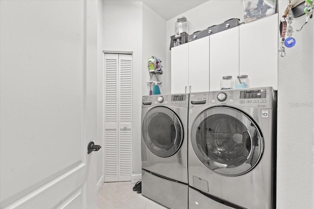 washroom with light tile patterned floors, washing machine and dryer, and cabinet space