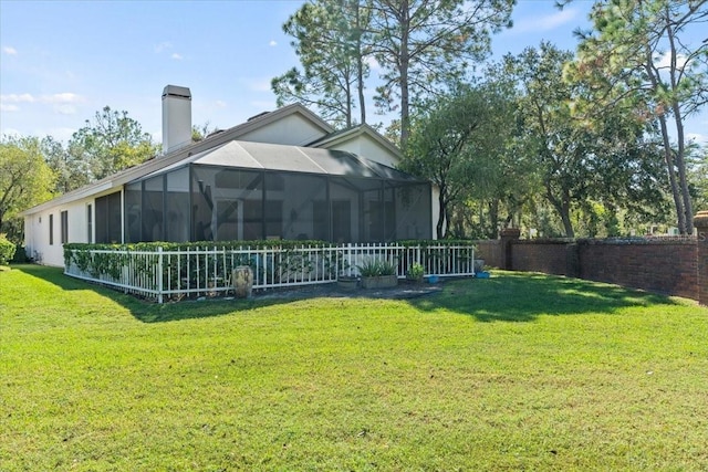 rear view of property with glass enclosure, a yard, fence, and a chimney