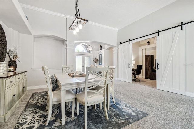 dining area featuring arched walkways, crown molding, decorative columns, light colored carpet, and a barn door