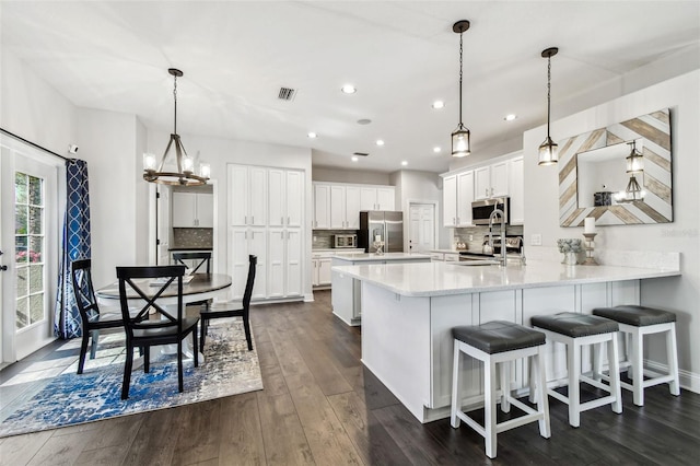 kitchen featuring a peninsula, visible vents, white cabinets, appliances with stainless steel finishes, and dark wood finished floors