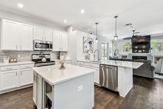 kitchen featuring visible vents, appliances with stainless steel finishes, open floor plan, a peninsula, and a sink