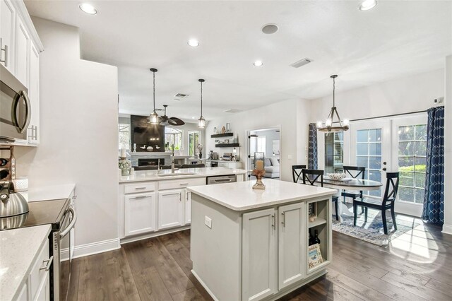 kitchen featuring a kitchen island, appliances with stainless steel finishes, dark wood finished floors, and a sink