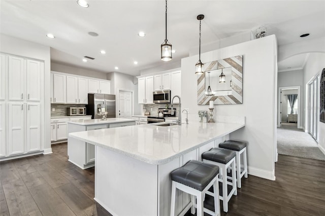 kitchen with stainless steel appliances, a breakfast bar, a peninsula, a kitchen island, and tasteful backsplash