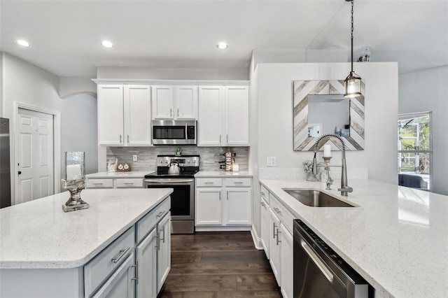 kitchen with stainless steel appliances, decorative backsplash, a sink, and white cabinets