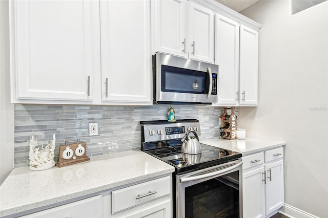 kitchen with stainless steel appliances, light stone counters, backsplash, and white cabinets