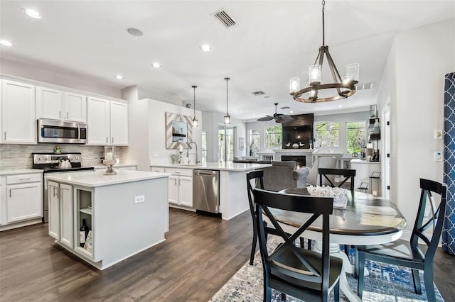 kitchen featuring white cabinetry, visible vents, appliances with stainless steel finishes, a center island, and tasteful backsplash