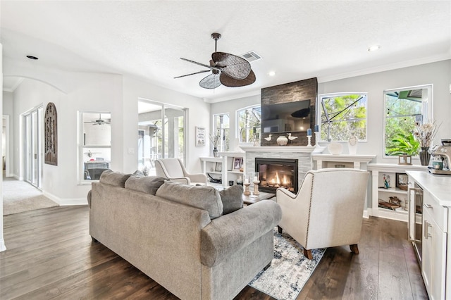 living room featuring a large fireplace, visible vents, dark wood finished floors, and a healthy amount of sunlight