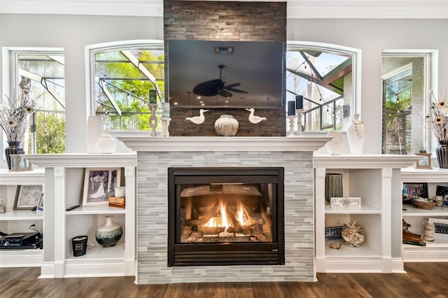 room details with a ceiling fan, a tiled fireplace, and wood finished floors