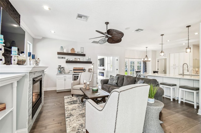 living area featuring dark wood-style flooring, a glass covered fireplace, visible vents, and recessed lighting