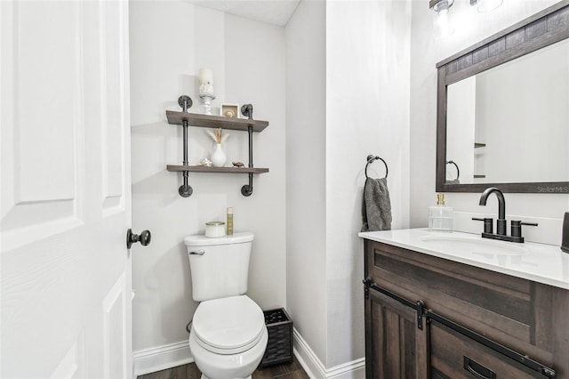 bathroom with wood finished floors, vanity, toilet, and baseboards