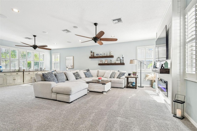 carpeted living area with a healthy amount of sunlight, visible vents, and baseboards