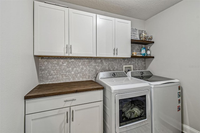 laundry area featuring a textured ceiling, washing machine and dryer, and cabinet space