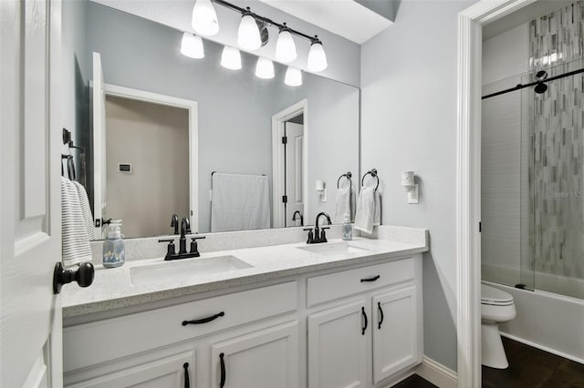 bathroom featuring toilet, double vanity, enclosed tub / shower combo, and a sink