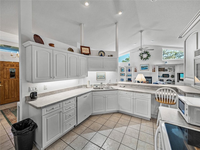 kitchen featuring white appliances, a sink, a ceiling fan, white cabinets, and vaulted ceiling