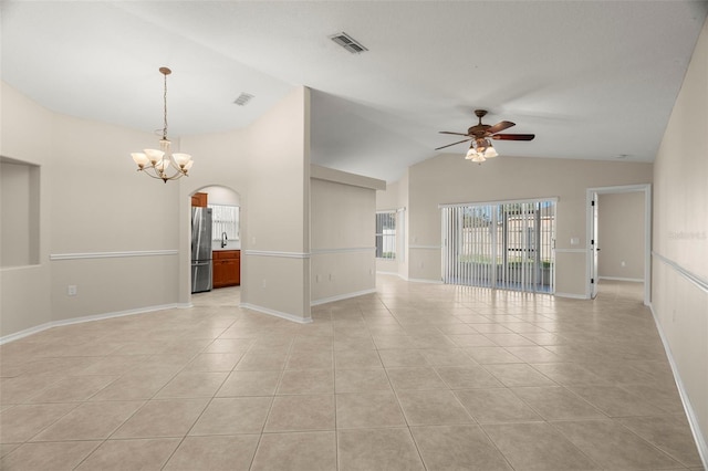 empty room with light tile patterned floors, arched walkways, lofted ceiling, ceiling fan with notable chandelier, and visible vents