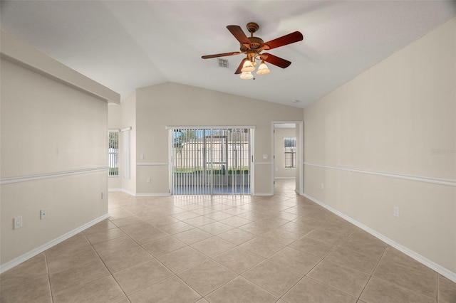 spare room featuring light tile patterned floors, lofted ceiling, visible vents, baseboards, and a ceiling fan