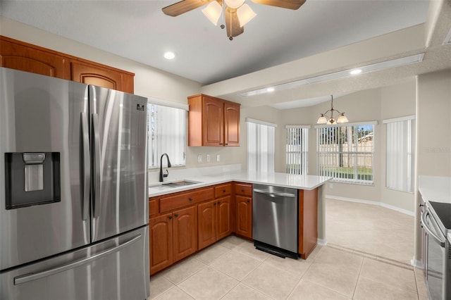 kitchen featuring stainless steel appliances, brown cabinetry, a peninsula, and a sink