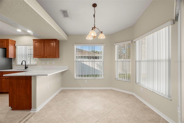 kitchen featuring light tile patterned floors, a sink, visible vents, light countertops, and brown cabinetry