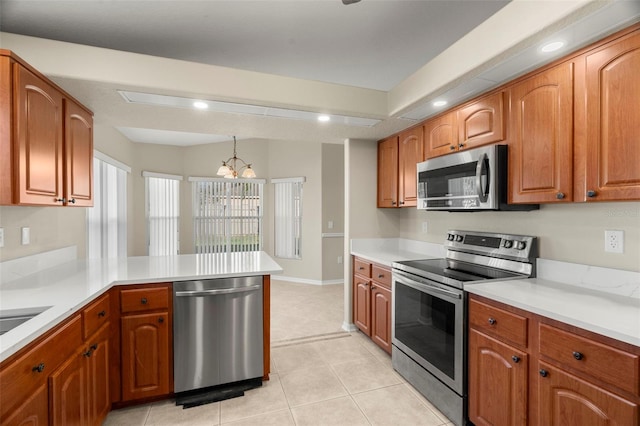 kitchen featuring stainless steel appliances, a peninsula, light countertops, and brown cabinets