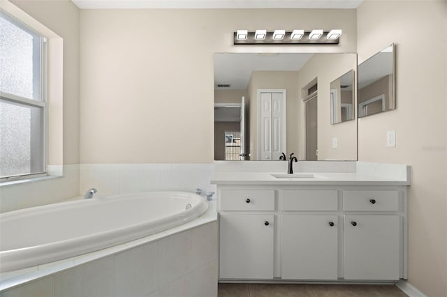 bathroom featuring tile patterned flooring, vanity, and a bath