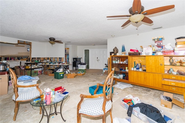 miscellaneous room featuring visible vents, a textured ceiling, unfinished concrete floors, and a ceiling fan