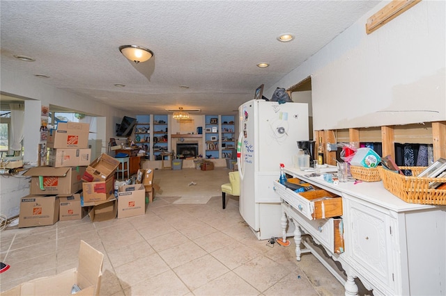 kitchen featuring a textured ceiling, light tile patterned flooring, a fireplace, and freestanding refrigerator