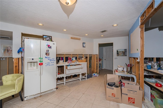 kitchen with light tile patterned flooring, recessed lighting, a textured ceiling, and white refrigerator with ice dispenser