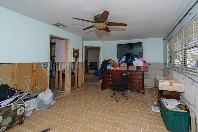 interior space with visible vents, wood tiled floor, wainscoting, ceiling fan, and a textured ceiling